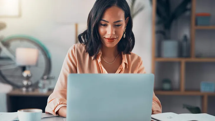 Woman working on laptop online, checking emails and planning on the internet while sitting in an office alone at work. Business woman, corporate professional or manager searching the internet