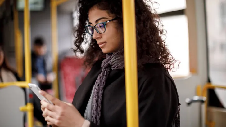 Young woman traveling by bus and using smart phone