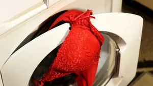 Rode bh op het deurtje van een automatische wasmachine.