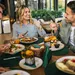 Groep vrienden is samen aan het eten in een restaurant. Ze eten salades, hamburgers, brood en vlees.