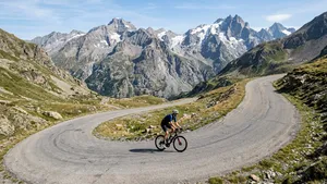 Eenzame mannelijke wielrenner met helm fietst in alle rust over een smalle, verlaten bergweg in de Franse Alpen.