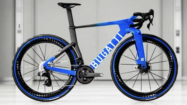 De exclusieve blauwe Factor x Bugatti racefiets, gefotografeerd in zijaanzicht tegen een minimalistische betonnen achtergrond.