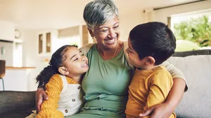 Hug, grandmother or happy kids on a sofa with love enjoying quality bonding time together in family home. Smile, affection or funny senior grandparent with children siblings on house couch laughing