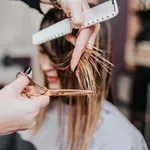 Beautiful young woman getting her haircut by a hairstylist at a beauty salon.