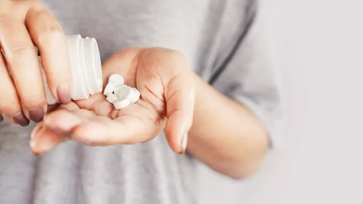 closeup woman hand holding medicine bottle taking overdose pills