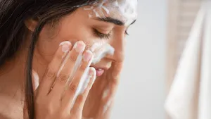 Vrouw die haar gezicht wast met water in een badkamer.