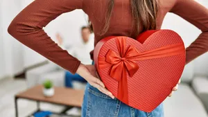 Young hispanic couple smiling happy surprising with valentine gift at home.