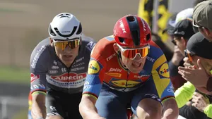 Mathieu van der Poel in het wiel van Mads Pedersen tijdens een koers, met toeschouwers langs de kant van de weg.