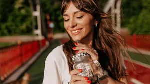 Close up outdoor portrait of beautiful lovely charming girl with long hair closed eyes and smiling while drinking morning coffee