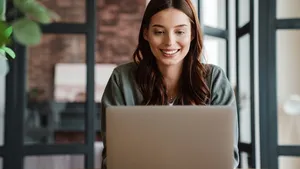 Beautiful smiling woman working with laptop while sitting at table