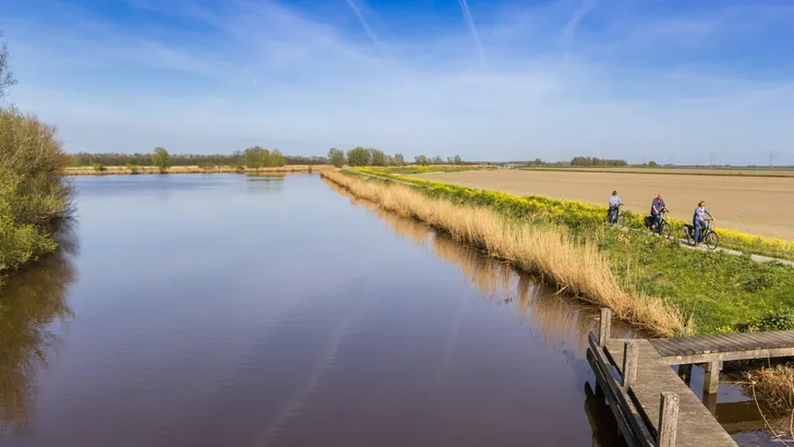 People riding a bicycle along the canal in Winschoten