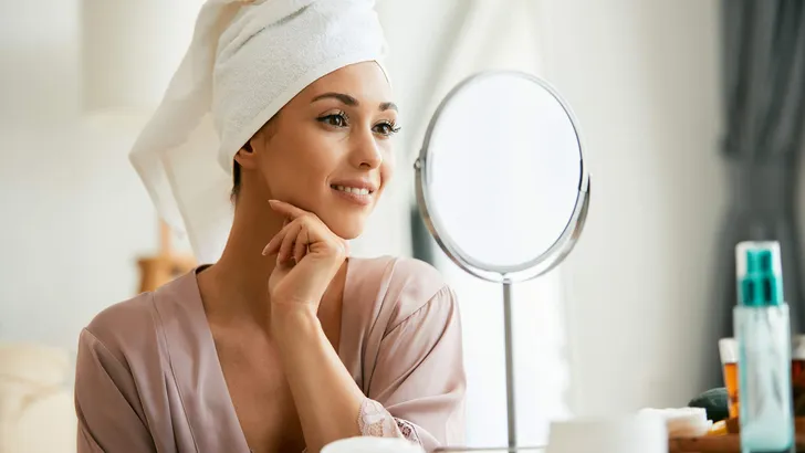 Young beautiful woman looking herself in a mirror at home.