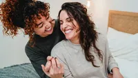 Happy gay women couple celebrating together with engagement ring in bed - Soft focus on right lesbian girl face