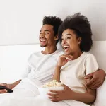 Couple sitting in bed together eating popcorn