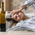 Glass and bottle of wine on table of drunk woman