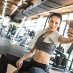 Young sportswoman taking selfie after sports training in gym