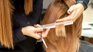 Hairdresser cuts hair to young woman