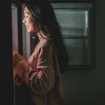 an asian chinese female looking for food from the refrigerator during mid night in the kitchen holding a plate