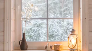 Sfeervolle brandende kaarsen en kerstverlichting op de vensterbank binnen.