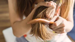 Woman combing tangled hair, Hair problems concept