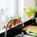 Woman pouring dish soap on sponge