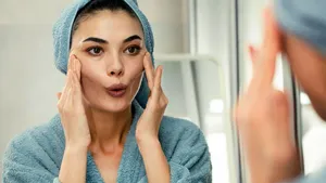 Een vrouw die face yoga aan het doen is in de spiegel