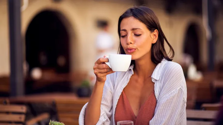 Young pretty woman enjoying drinking coffee