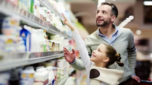 Meisje wijst naar een product op een bovenste plank in de supermarkt.