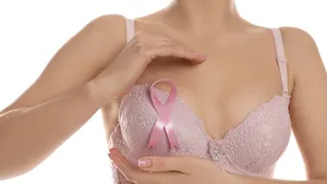 Woman with pink ribbon on white background, closeup. Breast cancer awareness