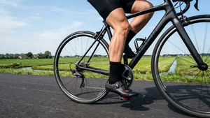 Een close-up van de benen en pedalen van een amateurwielrenner die met een perfecte uitlijning en soepele trapfrequentie fietst.