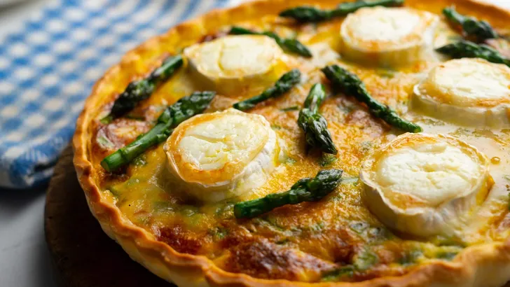 French style quiche with green asparagus, eggs, and slices of goat cheese.