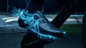 Close-up van een futuristische, zwarte wielerschoen, ingeklikt op een pedaal. Over de schoen lopen subtiele, blauw oplichtende lijnen die de slimme technologie symboliseren, tegen een donkere achtergrond die snelheid suggereert.