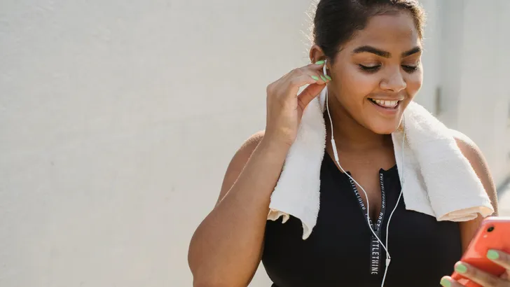 Smartphone vrouw met handdoek om nek en oortjes in