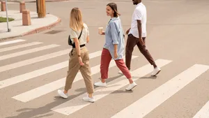 Young happy intercultural friends having drinks and talking while crossing road