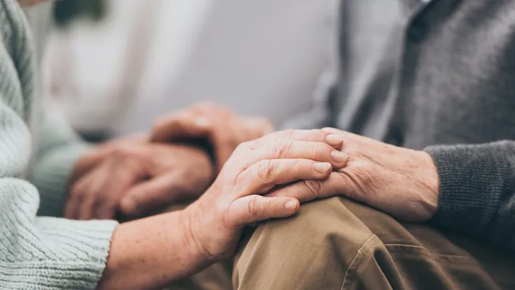 cropped view of retired couple holding hands