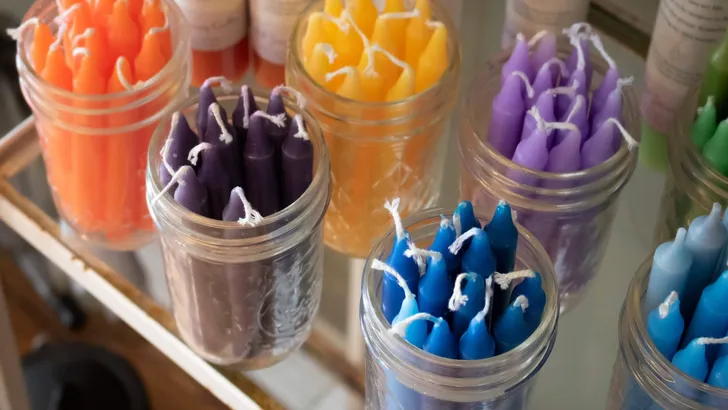 glass jars filled with long colorful candles on a shop shelf