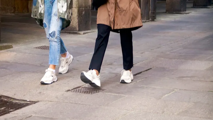 Young elegant women walking on the street wearing sport shoes.