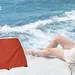 Samengesteld beeld met foto van vrouw bij strand en op voorgrond productfoto's van roestbruine top en shorts van Zeeman.