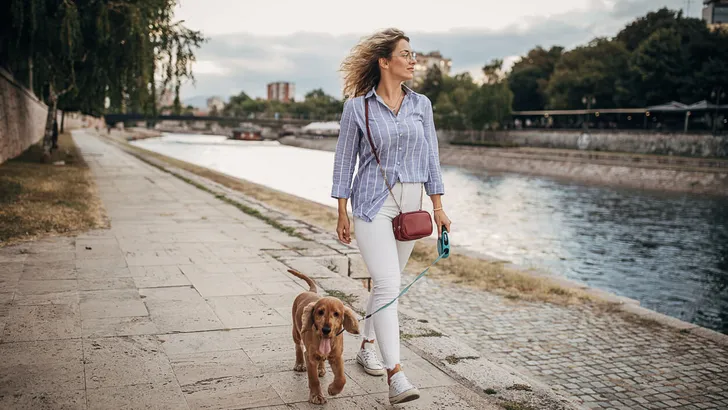 Beautiful woman walking her dog by the river