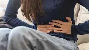 young woman gripping her stomach have abdominal pain .