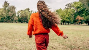 Horizontal rear view of a young woman walking with blowing long