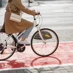 woman cycling along red bike lane road in city