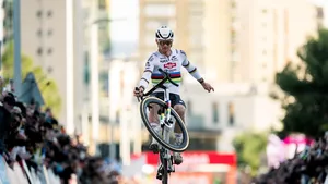 Mathieu van der Poel in regenboogtrui maakt eenhandige wheelie als demonstratie van ultieme fietsbeheersing