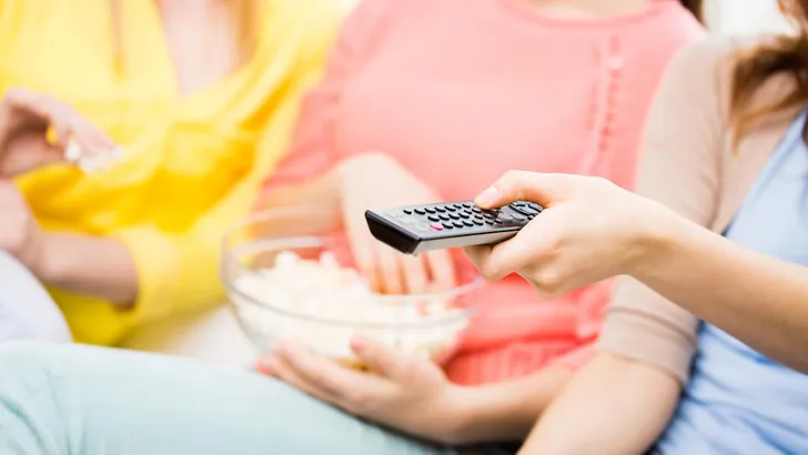 close up of teenage girls with remote watching tv