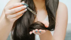 Close-up vrouw druppelt haarolie voor droog haar.