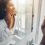 Pleased lady in a bathrobe staring at her reflection