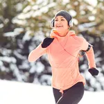 Woman jogging in the snow on the nature in winter