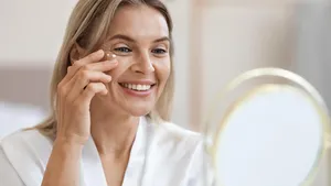 Closeup of cheerful beautiful adult lady applying eye cream