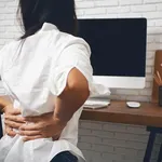 Business woman suffering from back pain in office home