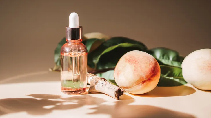 Fruitige parfums – foto van parfumflesje op een tafel bij perziken